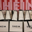 SHEIN shopping bags displayed in front of a branded wall