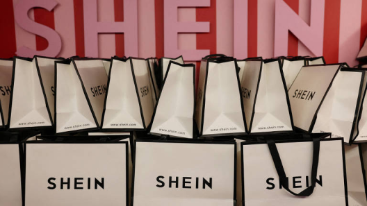 SHEIN shopping bags displayed in front of a branded wall